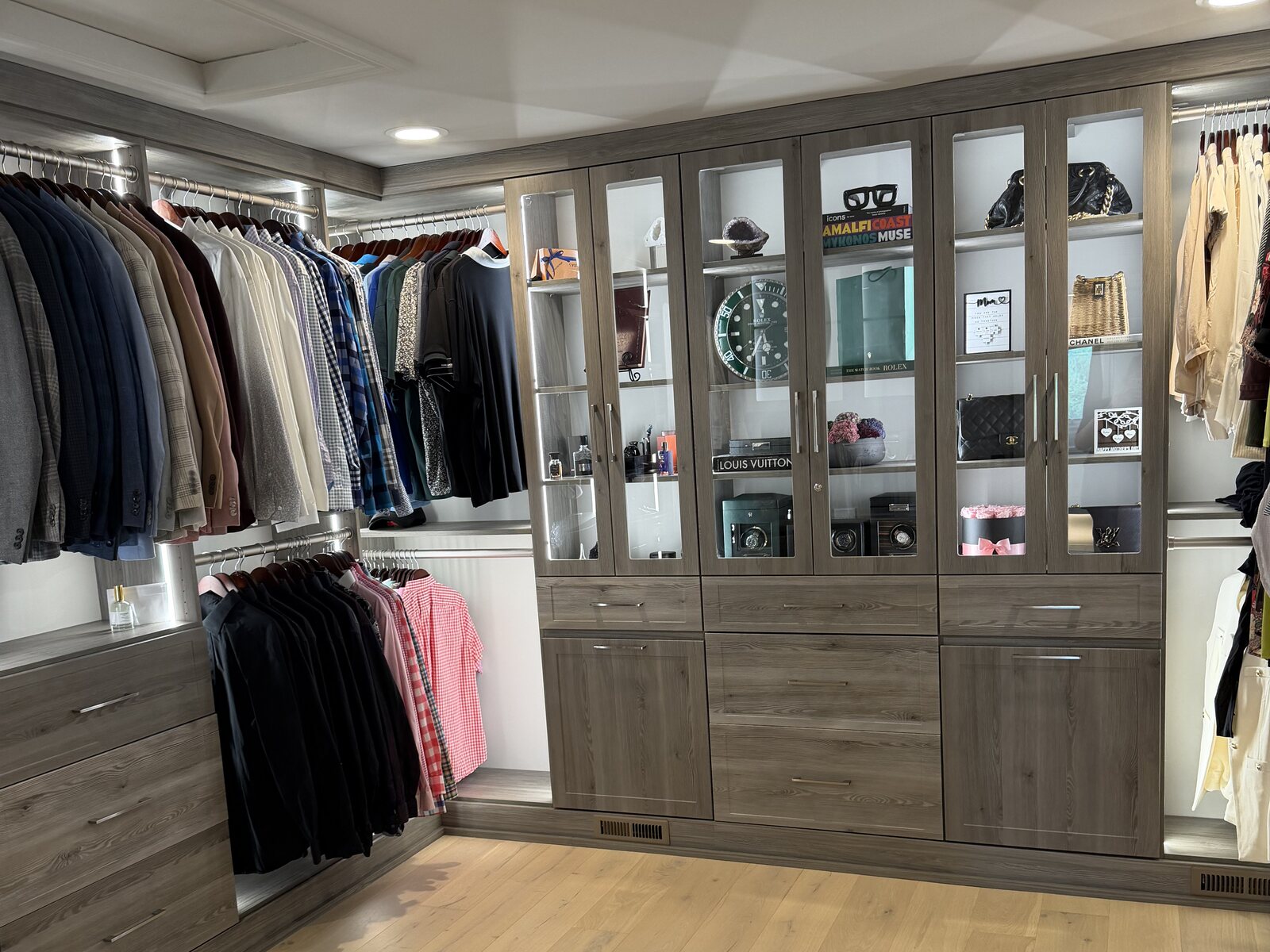 Walk-in closet with greige cabinetry, glass-front display cabinets and built-in drawers